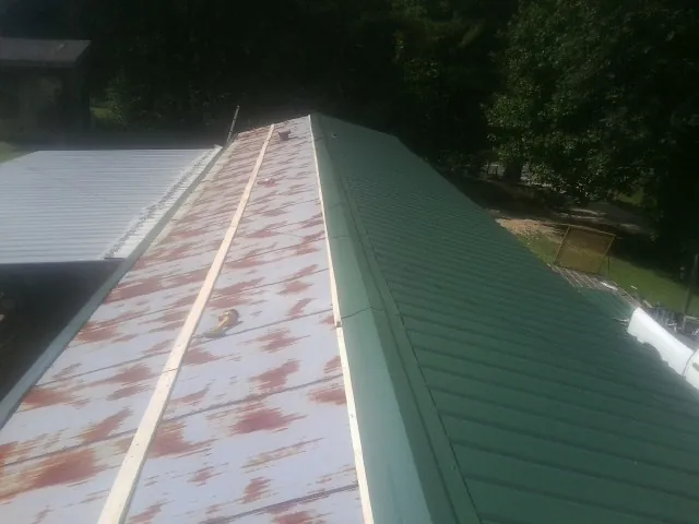 Old rusted panels beside newly installed green metal roofing — Wind Damage Roof Repair by Roofing Brothers in Dresden